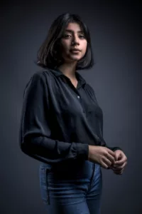 Portrait studio sur fond gris foncé d'une jeune femme en chemise noire et cheveux foncés mi-longs