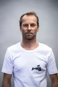 Portrait studio sur fond gris clair d'un moniteur de surf en t-shirt blanc