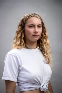 Portrait studio sur fond gris clair d'une surfeuse avec de long cheveux blonds bouclés