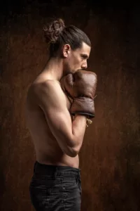 Portrait studio conceptuel sur fond brun d'un boxeur en concentration avant un combat